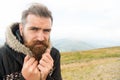 Bearded man, brutal caucasian hipster with moustache cold on mountain