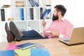 Bearded man with brutal look relax at work desk drinking coffee in modern office, hipster