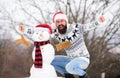 Bearded man build snowman. happy hipster ready to celebrate xmas. winter season activity. man santa hat play with snow