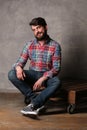 Bearded man in colorful shirt and jeans sitting on a deck