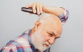 Bearded man cutting his own hair with a clipper. Man hair treatment. Gray man hair clippings. Bald man hairclipper