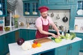 Bearded man cutting vegetables and cooking salad in kitchen interior. Man in chef uniform cooking vegetables at home kitchen Royalty Free Stock Photo
