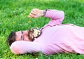 Bearded man with daisy flowers in beard lay on grassplot, grass background. Allergy and antihistamine concept. Man with