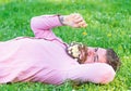 Bearded man with daisy flowers in beard lay on grassplot, grass background. Allergy and antihistamine concept. Man with