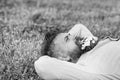 Bearded man with daisy flowers in beard lay on meadow, grass background. Hipster with bouquet of daisies in beard Royalty Free Stock Photo