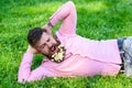 Bearded man with daisy flowers in beard lay on meadow, lean on hand, grass background. Hipster with bouquet of daisies Royalty Free Stock Photo