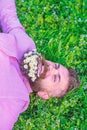 Bearded man with daisy flowers lay on grassplot, grass background. Hipster with bouquet of daisies in beard relaxing Royalty Free Stock Photo