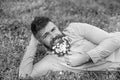 Bearded man with daisy flowers lay on meadow, lean on hand, grass background. Masculinity concept. Hipster with daisies Royalty Free Stock Photo