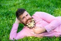 Bearded man with daisy flowers lay on meadow, lean on hand, grass background. Masculinity concept. Hipster with daisies Royalty Free Stock Photo