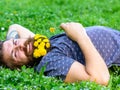 Bearded man with dandelion flowers lay on meadow, grass background. Man with beard on smiling face enjoy nature. Hipster Royalty Free Stock Photo