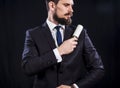 Bearded man in dark suit holds sticky brush for cleaning