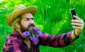 Bearded man with decorated beard making selfie on smartphone. Handsome male with beard of flowers. Royalty Free Stock Photo