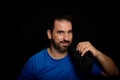 Bearded man dressed in blue t-shirt posing against black background Royalty Free Stock Photo