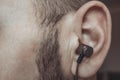 Bearded man with earphone in the ear close up. Royalty Free Stock Photo