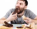 Bearded man eating cupcakes with pleasure after a diet. harmful but delicious food