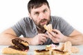 Bearded man eating cupcakes with pleasure after a diet. harmful but delicious food