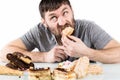 Bearded man eating cupcakes with pleasure after a diet. harmful but delicious food