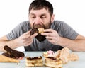 Bearded man eating cupcakes with pleasure after a diet. harmful but delicious food