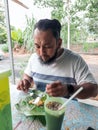 Bearded man eating nasi lemak at the local stall in the morning