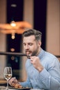 Bearded man eating seafood at the restaurant and looking involved