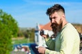 Bearded man with espresso mug, drinks coffee. Man with beard and mustache on strict face drinks coffee, urban background Royalty Free Stock Photo