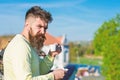 Bearded man with espresso mug, drinks coffee. Man with beard and mustache on strict face drinks coffee, urban background Royalty Free Stock Photo