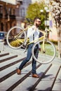 Bearded man with fix bicycle. View of confident young bearded man carrying his bicycle on shoulder and looking away while walking