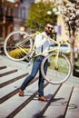 Bearded man with fix bicycle. View of confident young bearded man carrying his bicycle on shoulder and looking away while walking