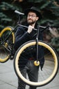 Bearded man with fixie bicycle. Low angle view of confident young bearded man carrying his bicycle on shoulder and looking away