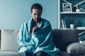 Bearded Man with Flue Sitting on Sofa at Home.