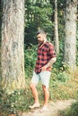 Bearded man in forest. Hipster with long beard on natural green landscape. Tourist in plaid shirt and jean shorts travel Royalty Free Stock Photo