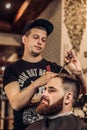 Bearded man getting beard haircut by hairdresser