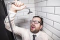 Bearded man with glasses and clothes closed his eyes and leaned against the wall of the bathroom, pouring himself out of a Royalty Free Stock Photo