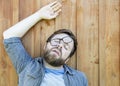 Bearded man in glasses was tired, lay down to rest on the wooden floor and fell asleep with his mouth open, in a funny pose, Royalty Free Stock Photo