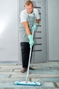 Bearded man in gloves with mop in hand cleaning floor in the house Royalty Free Stock Photo