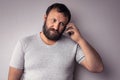 Bearded man in gray t-shirt holding mobile phone, using smartphone, making a call Royalty Free Stock Photo