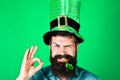 Bearded man in green top hat with clover in mouth showing sign ok. Saint Patrick's day celebration. National Irish Royalty Free Stock Photo