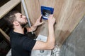 Male plumber installing toilet flush system in bathroom.