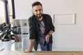 Bearded man holding smartphone and smiling at camera in office Royalty Free Stock Photo