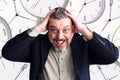 Bearded man holds his head in both hands. Against the background of the clock. Lack of time. Do not do business.