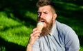 Bearded man with ice cream cone. Delicacy concept. Man with long beard eats ice cream, while sits on grass. Man with Royalty Free Stock Photo