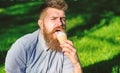 Bearded man with ice cream cone. Delicacy concept. Man with long beard eats ice cream, while sits on grass. Man with Royalty Free Stock Photo