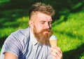 Bearded man with ice cream cone. Temptation concept. Man with beard and mustache on calm face enjoy ice cream, grass on