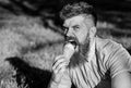 Bearded man with ice cream cone. Temptation concept. Man with long beard eats ice cream, while sits on grass. Man with Royalty Free Stock Photo