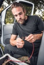 Man inside a van using heat shrink tubing on a electrical cable