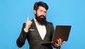 Bearded man with laptop computer pointing finger up. Businessman with notebook in office.