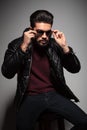 Bearded man in leather jacket is putting on his sunglasses Royalty Free Stock Photo