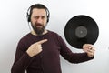 Man listening to music using headphone holding vinyl disc   with happy face winking at the camera pointing with hand and finger Royalty Free Stock Photo