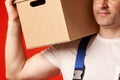 Bearded man in a loader work suit holds a cardboard box on his shoulder Royalty Free Stock Photo