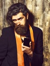 Caucasian hipster in suit holding perfume on brown vintage wooden studio background